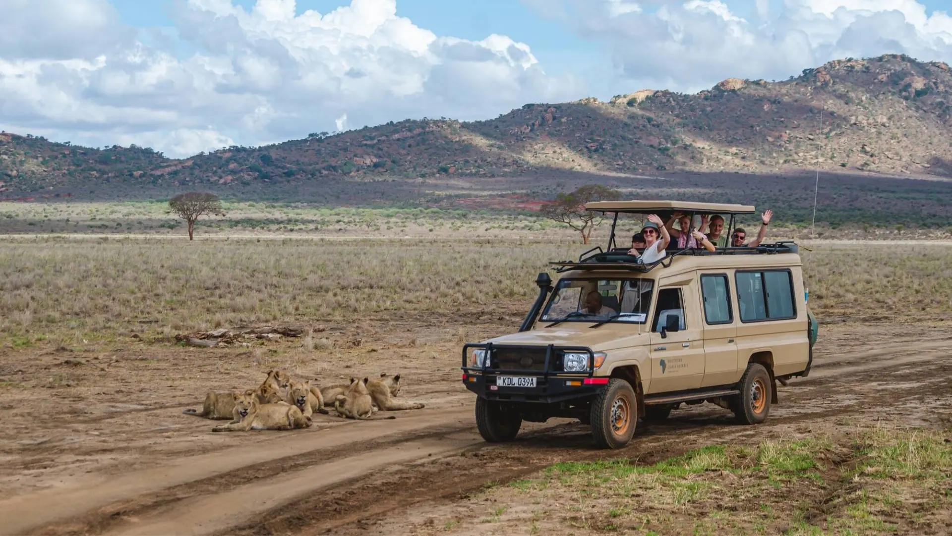 Safari vehicle on a track below dry hills in northern Kenya