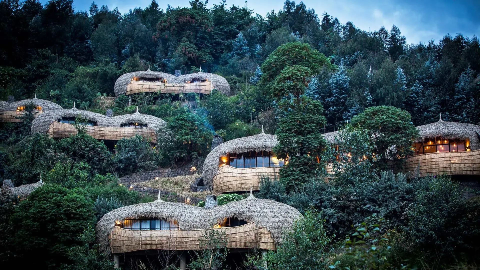 Thatched villas set into a forested hillside in northern Rwanda